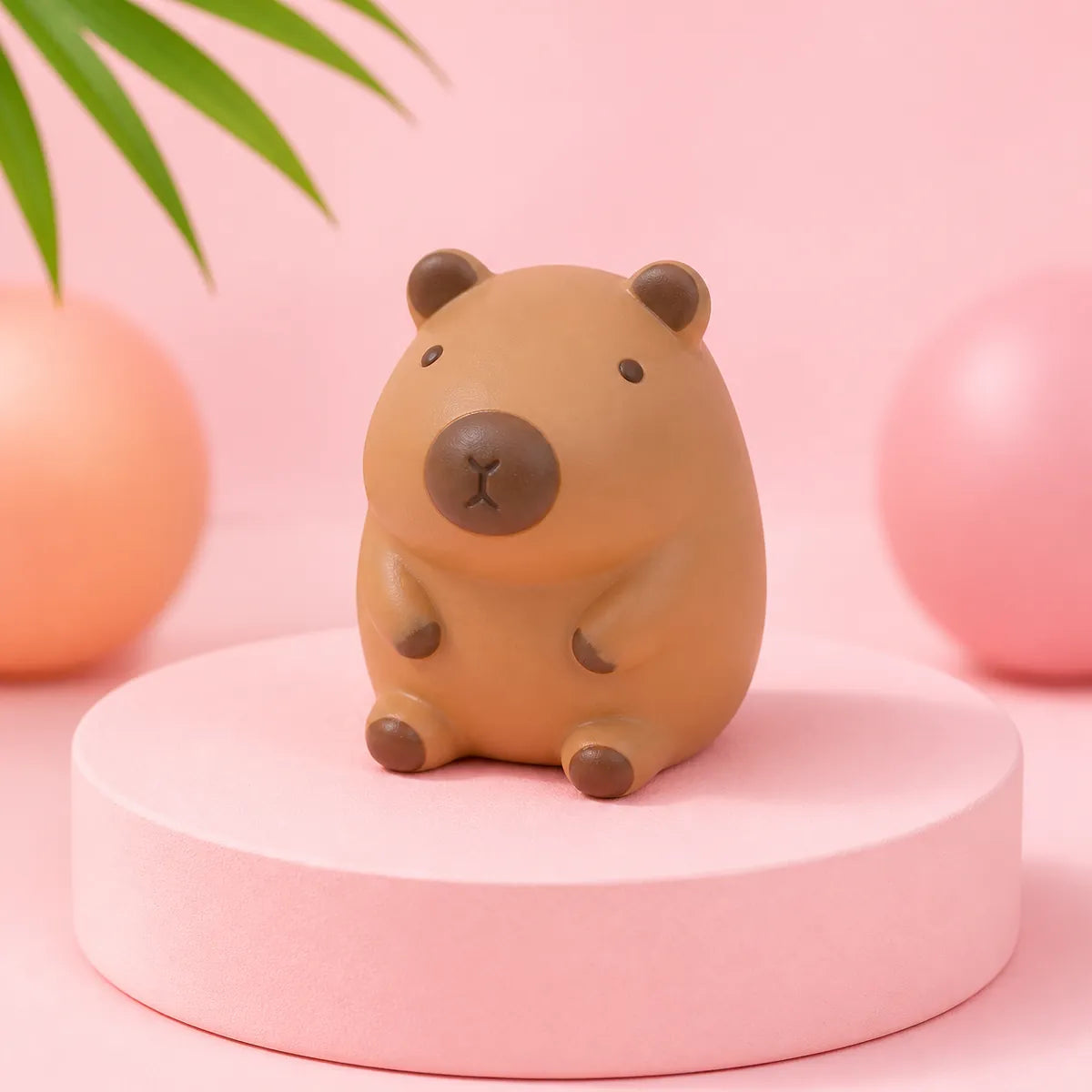 Brązowy gniotek squishy w kształcie kapibary na różowym podeście