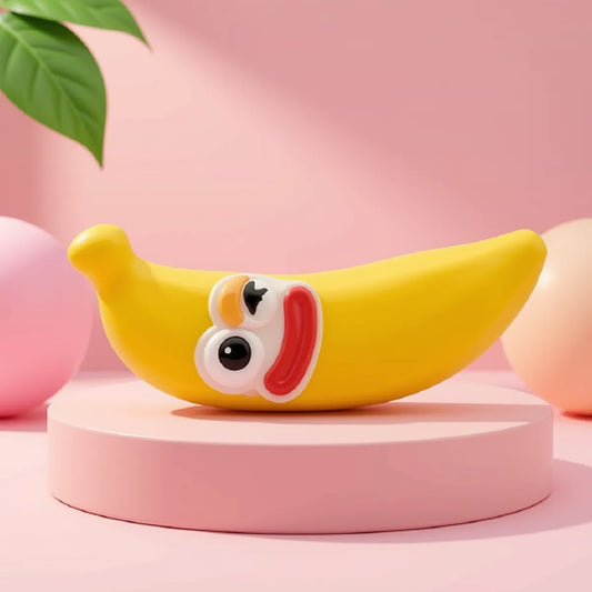Żółty gniotek squishy w kształcie banana z uśmiechniętą buźką leżący na różowym podeście