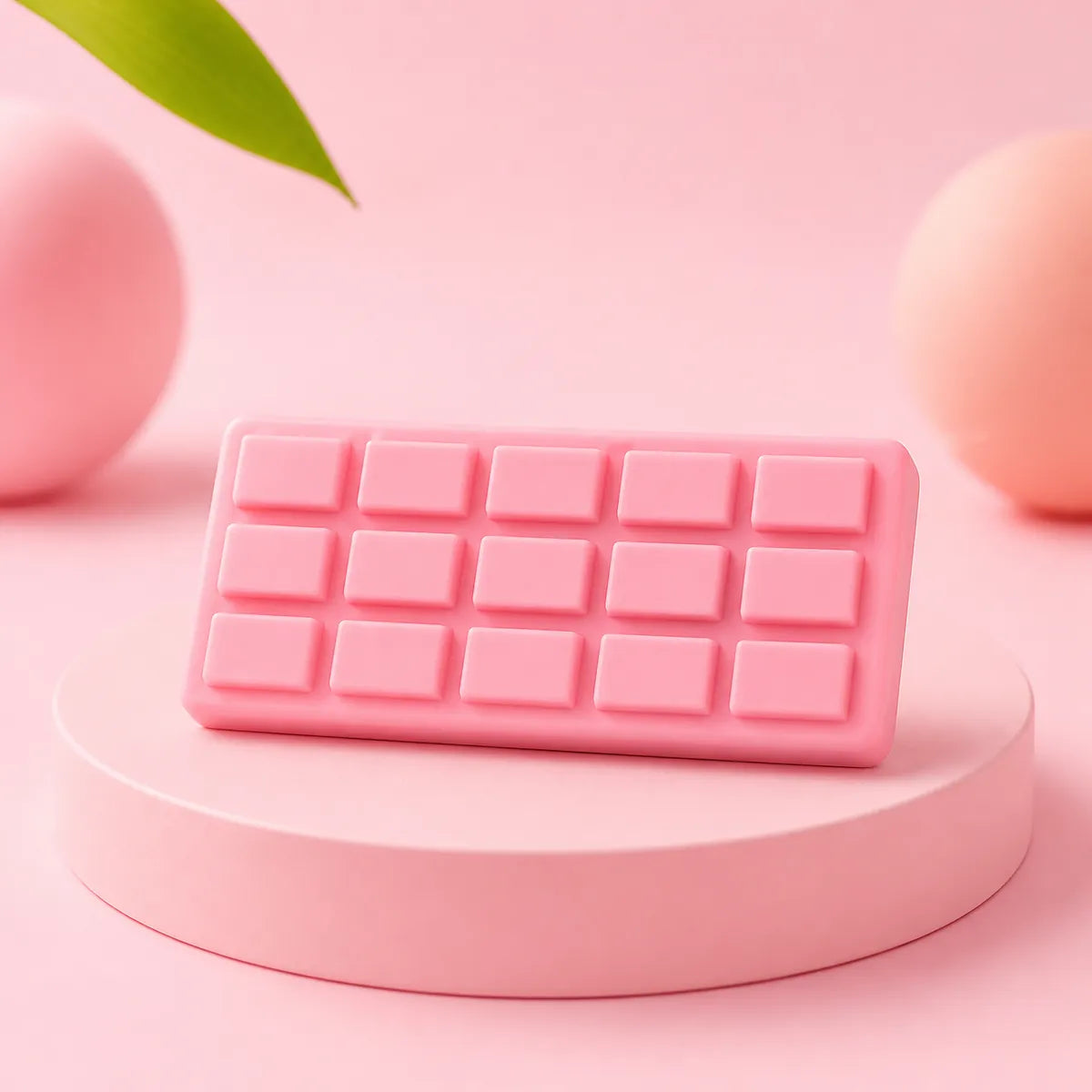 Różowy gniotek squishy w kształcie tabliczki czekolady z kostkami na różowym podeście