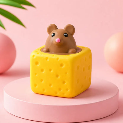 Żółty gniotek squishy w kształcie kostki sera z brązową myszką wyglądającą z góry na różowym podeście